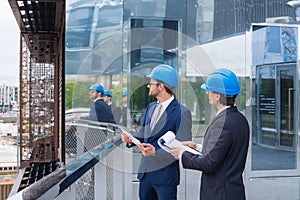 Real estate developers in helmets. New office construction. Confident business men and architect talking in front of