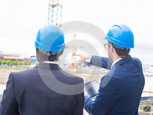 Real estate developers in helmets. New office construction. Confident business men and architect talking in front of