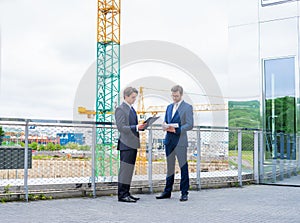 Real estate developers in helmets. New office construction. Confident business men and architect talking in front of