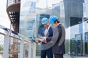 Real estate developers in helmets. New office construction. Confident business men and architect talking in front of