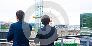 Real estate developers in helmets. New office construction. Confident business men and architect talking in front of