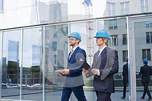 Real estate developers in helmets. New office construction. Confident business men and architect talking in front of