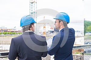 Real estate developers in helmets. New office construction. Confident business men and architect talking in front of