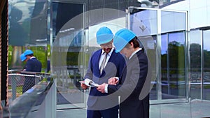 Real estate developers in helmets. New office construction. Confident business men and architect talking in front of