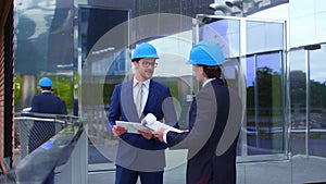 Real estate developers in helmets. New office construction. Confident business men and architect talking in front of