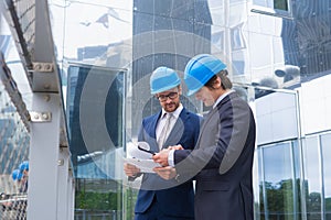 Real estate developers in helmets. New office construction. Confident business men and architect talking in front of