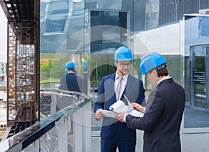 Real estate developers in helmets. New office construction. Confident business men and architect talking in front of