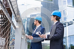 Real estate developers in helmets. New office construction. Confident business men and architect talking in front of