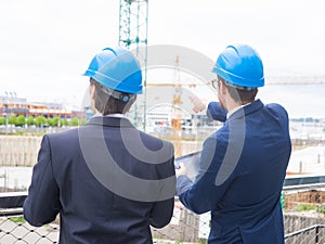 Real estate developers in helmets. New office construction. Confident business men and architect talking in front of