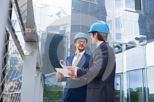 Real estate developers in helmets. New office construction. Confident business men and architect talking in front of