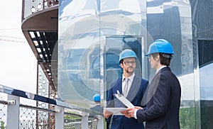 Real estate developers in helmets. New office construction. Confident business men and architect talking in front of