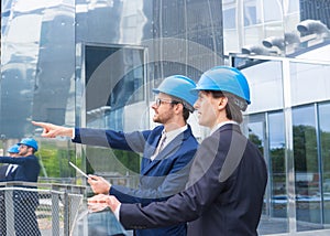 Real estate developers in helmets. New office construction. Confident business men and architect talking in front of