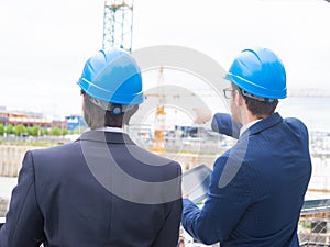 Real estate developers in helmets. New office construction. Confident business men and architect talking in front of