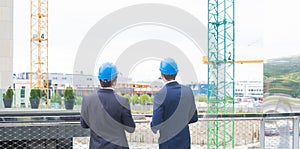 Real estate developers in helmets. New office construction. Confident business men and architect talking in front of