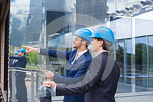 Real estate developers in helmets. New office construction. Confident business men and architect talking in front of