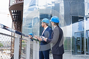 Real estate developers in helmets. New office construction. Confident business men and architect talking in front of