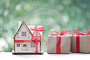 Real estate and Gift new home concept,Model house and gift box with red ribbon on green background.