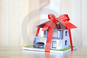 Real estate and Gift new home concept,Model house with Red ribbon and key on wooder background