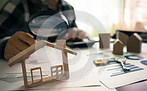 Real estate or House Appraisal using magnifying glass over the model of a wooden house. Concept of House Search for housing and