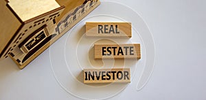 Real estate investor symbol. Wooden blocks with words `Real estate investor` near miniature house. Beautiful white background. photo