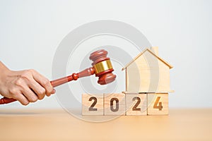 Real Estate Law, Home Insurance, property Tax, Auction and Bidding concepts. 2024 year block with small toy house model with gavel