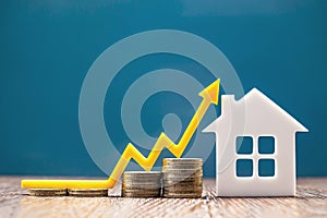 Real estate market, graph, up arrow. House model and a stack of coins. The concept of inflation, economic growth, the