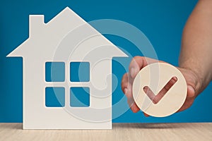 Real estate mortgage approval. Check mark icon in hand and house model as a symbol of a successful real estate purchase