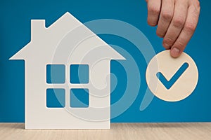 Real estate mortgage approval. Check mark icon in hand and house model as a symbol of a successful real estate purchase