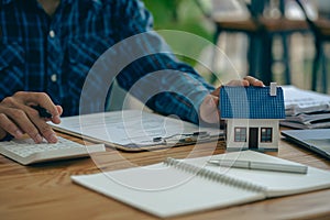 Real estate office, home sales agent sitting at desk with contract documents and house