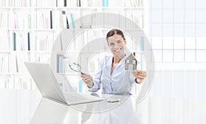 Real estate office, smiling woman agent working on computer with