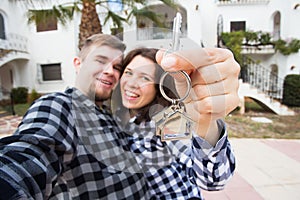 Real estate and property concept - Happy couple holding keys to new home and house miniature