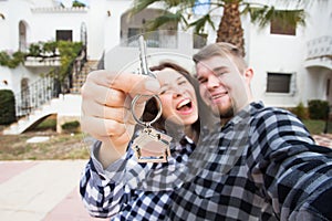 Real estate and property concept - Happy couple holding keys to new home and house miniature