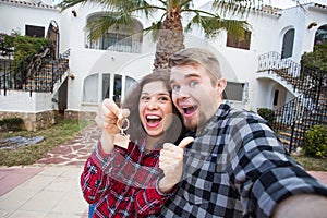 Real estate and property concept - Happy couple holding keys to new home and house miniature