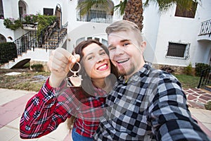 Real estate and property concept - Happy couple holding keys to new home and house miniature