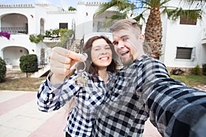 Real estate and property concept - Happy couple holding keys to new home and house miniature