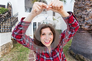 Real estate and property concept. Happy ownership. Attractive young woman holding keys while standing outdoor against