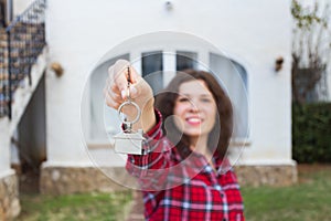 Real estate and property concept - Happy young woman in front of new home with new house keys
