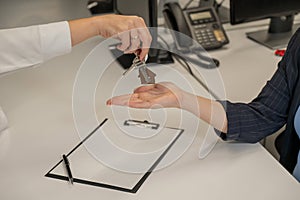 Real estate purchase transaction. The realtor hands the woman the keys to the house. Close-up of hands.