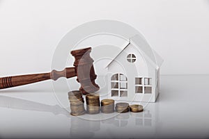 Real estate sale auction concept. Wooden gavel and house model with coins