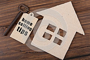Real estate sale concept - old key tag with text Home selling tips and cardboard house