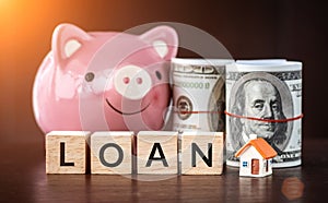 Real estate sale, savings, home loans market concept. model house with text loan on wooden cube, smilely pink Piggy bank