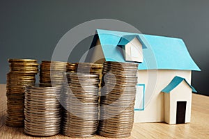 Real estate value. Model of house and stacks of coins.