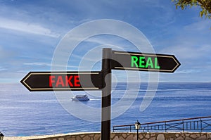 Real or fake symbol. Concept word Real or Fake on beautiful signpost with two arrows. Beautiful blue sea sky with clouds