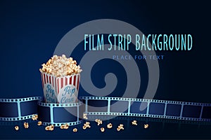 Real film strip frame in wave form with popcorn box isolated on blue background. Cinema template with space for your text. 3D