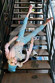 Real girl looks like a barbie doll in shop is on sale. Girl fals from stairs dressed in pastel blue and pink colors