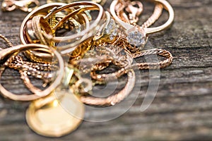 Real gold rings with diamond on weathered pine wood board close up macro shot, focus on the neckless