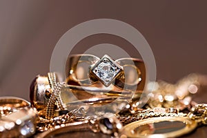 Real gold rings with diamonds, gems, neckless on dark cracked wood background