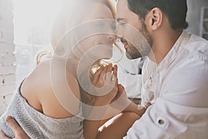 Real love. Beautiful young couple bonding and smiling while sitting in the bedroom