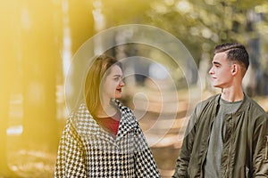 Real love. Beautiful young couple holding hands and keeping eye contact on sunny autumn day in park.