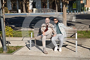 Real marriage of gay couple, holding hands, sitting on a wooden bench, talking accomplices and happy. Concept lgtb, lgtbiq+,